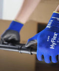 Person wearing HyFlex 11-618 Ultra Thin Nylon Safety Gloves For Automotive And Fabrication in Size 11 2XL, handling metal rod.