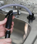 Built Tough Replacement Kitchen Faucet Spray Hose Coupled With 48 Inch Heavy Vinyl Line and Smooth Swivel Joint Black Handheld Sprayer being held.