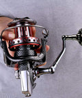 Person holding Surf Spinning Reel Size 10000 12000 For Saltwater Fishing With Full Metal Frame, showing details and handle design.