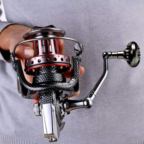 Person holding Surf Spinning Reel Size 10000 12000 For Saltwater Fishing With Full Metal Frame, showing details and handle design.