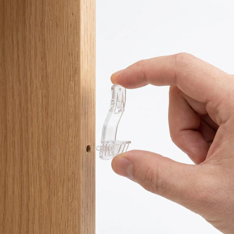 Hand holding 24 pack locking shelf pins with anti slip grooves, curved long rectangular shelf supports for 20mm thick cabinets, clear plastic pegs.