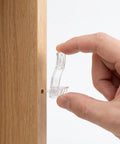 Hand holding a piece from 24 Pack Plastic Cabinet Shelf Clips With Self Locking Design Curved Long Rectangular Pins 6.4mm Anti Slip Grooves