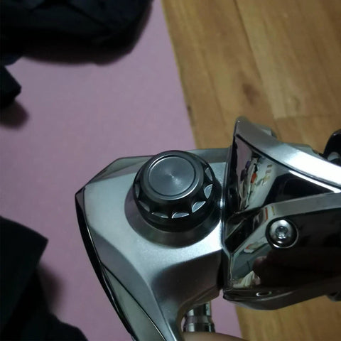 Close-up of aluminum alloy fishing reel cap replacement for spinning reels, precision screw nut accessory kit, installed view.