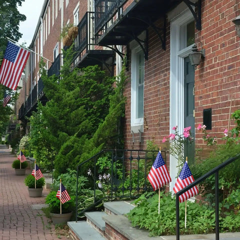 Pack Of 12 Small 8x12 Inch American Flags On Sticks With Kid Safe Spear Tops in front yard garden of brick houses