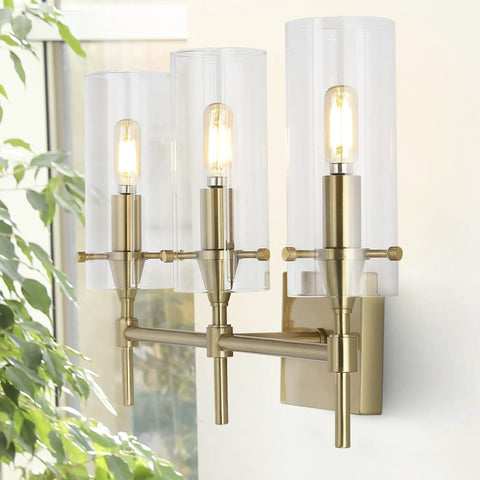 Brass Gold Modern Farmhouse LED Vanity Light Sconce With Clear Glass Cylinder Shade in living room setting