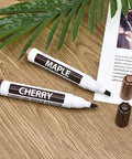 Maple and Cherry furniture repair markers on wooden surface. Focus keyword: Furniture Wood Repair Marker For Floors And Tables Easy DIY Scratch Fix Pen For Stains Quick Dry Long Lasting Professional Grade Wood Touch Up For Cabinets And Tables Black Finish