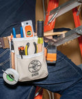 Person wearing Canvas And Leather 5 Pocket Tool Pouch With Chain Tape Thong And Tunnel Belt Connection Beige For Pros And DIYers Durable Riveted Construction Fits Belts Up To Two And A Quarter Inches with tools on belt next to ladder