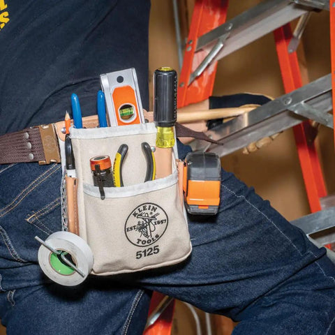 Person wearing Canvas And Leather 5 Pocket Tool Pouch With Chain Tape Thong And Tunnel Belt Connection Beige For Pros And DIYers Durable Riveted Construction Fits Belts Up To Two And A Quarter Inches with tools on belt next to ladder