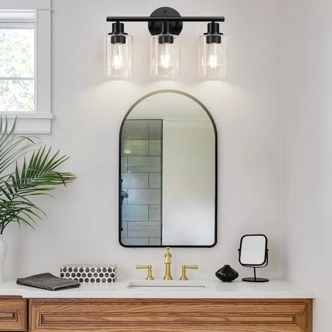 Three Light Matte Black Bathroom Vanity Light Fixtures With Clear Glass Shades above a modern mirror in a stylish bathroom.