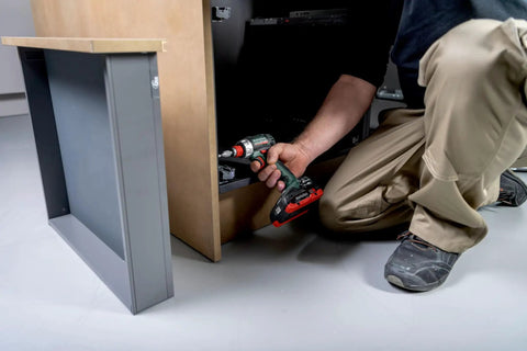 A professional using a Badass 18 Volt Cordless Brushless Drill Driver delivering 60 Newton Meters of torque for cabinet assembly.