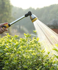 Person using 16 Inch Garden Watering Wand With 180 Degree Rotating Head And Thumb Control Shut Off Valve Eight Pattern Heavy Duty Hose Nozzle In Yellow Lightweight Aluminum And Zinc Alloy Construction For Easy Durable Yard Watering That Works Like A Charm on plants
