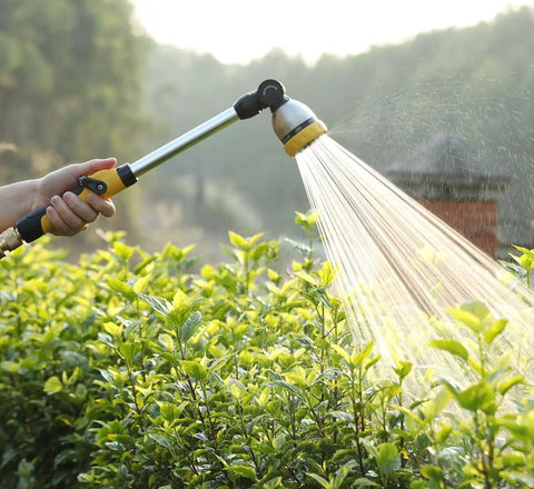 Person using 16 Inch Garden Watering Wand With 180 Degree Rotating Head And Thumb Control Shut Off Valve Eight Pattern Heavy Duty Hose Nozzle In Yellow Lightweight Aluminum And Zinc Alloy Construction For Easy Durable Yard Watering That Works Like A Charm on plants
