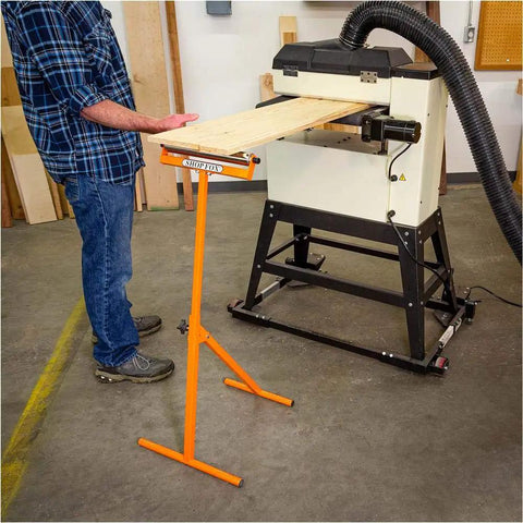 Person using D4800 Roller Stand With 12 Inch Ball Bearing Roller supporting a board in a workshop, orange finish visible.