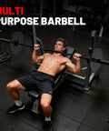 Man bench pressing with multi-purpose barbell in gym setup featuring weights and bench