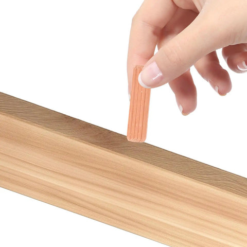 Hand holding a wooden dowel pin next to a wood surface, featuring Wooden Dowel Pins M8x30mm For Furniture Assembly Solid Round Dowels In Beige