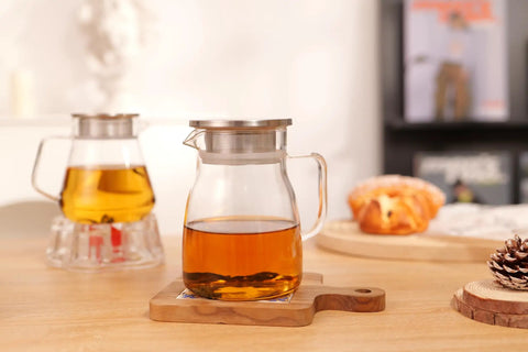 One Touch Glass Teapot 27 Oz 800 Ml Glass Tea Kettle With Stainless Steel Filter Lid on a wooden table with tea inside.
