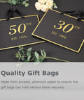 Black and gold 50th and 30th gift bags on a table with green leaves and flowers, featuring "Quality Gift Bags" text.