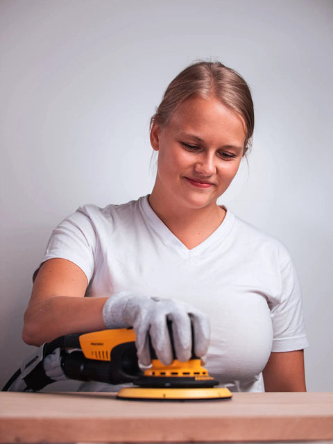 Top Tier 6 Inch Random Orbital Sander Featuring A Smooth Brushless Motor And Effective Dust Extraction Built For Rough Woodshop Jobs Drywall Sanding And Auto Detailing Comes With A Sturdy Zippered Case in use on wood surface by female user.