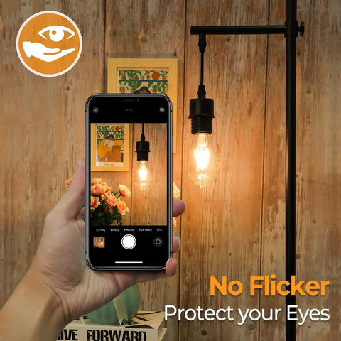 Hand holding smartphone with 4 Pack Vintage LED Edison Bulbs 60W Equivalent, 6W ST58 2700K Warm White in lamp fixture, clear glass
