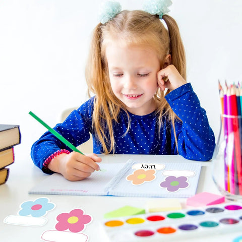 Girl writing with 180 Pcs Flower Name Tag Stickers Set For Back To School, pastel floral design nameplates on desk