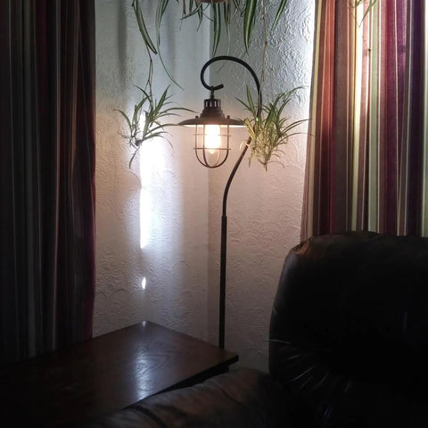 58 Inch Industrial Nautical Floor Lamp With Hanging Cage Shade, Brushed Pewter Finish in living room setting, next to couch and table