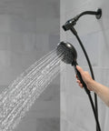 Hand using 6 Spray SureDock Magnetic Shower Head With Handheld, Matte Black Finish, showing water flow in bathroom