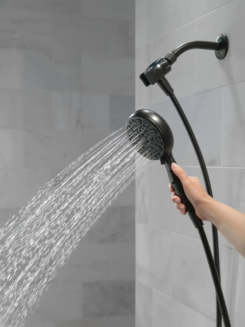 Hand using 6 Spray SureDock Magnetic Shower Head With Handheld, Matte Black Finish, showing water flow in bathroom