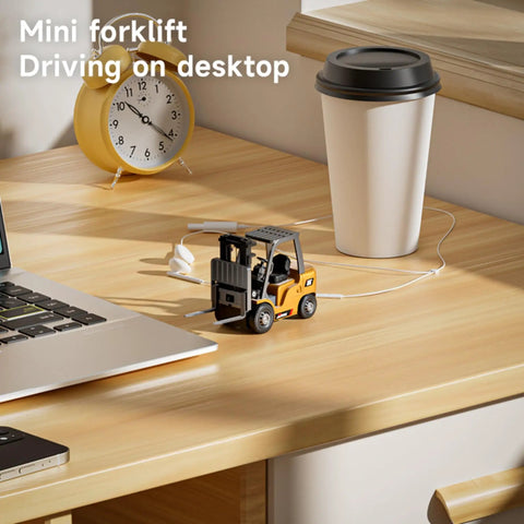 One Sixty Fourth Scale Alloy RC Forklift Toy With Lights And Sounds on a desk near a laptop and coffee cup