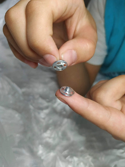 Hands holding 120 Sets Sew On Snap Buttons Metal Fasteners For Clothing Repair And DIY Sewing 8mm 10mm 13mm Sizes Stainless Steel Rust Resistant