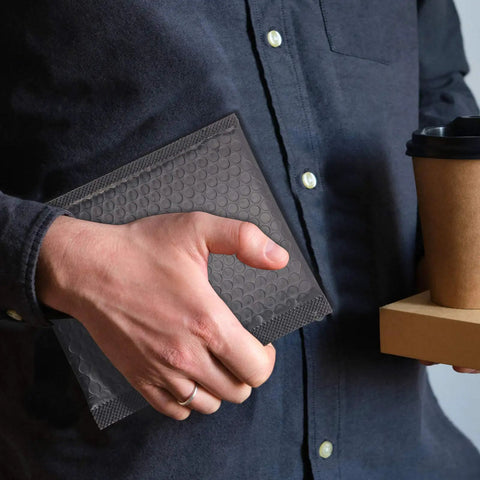 Person holding Black Bubble Mailers 40 Pack 7 By 5.2 Inch Padded Envelopes For Wrapping And Shipping Waterproof Lightweight Protection During Transit