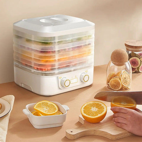 Big League Food Dehydrator Machine With Six Stackable Trays For Candy Snacks Beef Jerky Herbs on kitchen counter with sliced oranges.