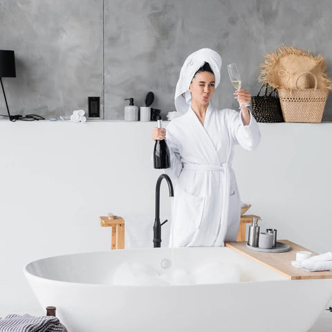 Woman in bathrobe holding champagne, beside freestanding bathtub and modern decor, near 10 Pack Slim GFCI Outlets 15A 125V With Self Test LED Indicator