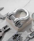 Single shackle from 4 Pack 1 Inch D Ring Shackles Bow Shackle With One And One Eighth Screw Pin Beefy Heavy Duty Tow Rigging Lifting Recovery Kit 8.5 Tons Working Load Limit Built For Winch Tow Moving with tools on a marble surface
