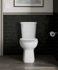 Elate Toilet Paper Holder In Brushed Nickel mounted in modern bathroom with sleek black tiles and toilet.