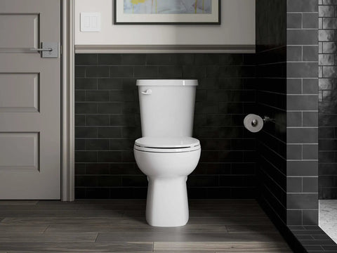 Elate Toilet Paper Holder In Brushed Nickel mounted in modern bathroom with sleek black tiles and toilet.