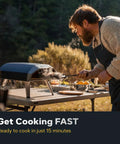 Man using Koda 12 Inch Gas Pizza Oven For Outdoor Cooking with 28 Millibar Regulator and Gas Hose Portable Oven on a patio table.