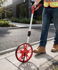 Hella Portable Foldable Distance Measuring Wheel With Bright Lcd Screen And Built In Carry Strap Rolls Out Smooth For Contractors And Handyman Teams in use on sidewalk.