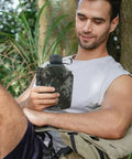Person holding Camouflage Insulated Water Bottle 1L With Strap And Thermal Lining Rugged Aluminum Hydration Flask outdoors