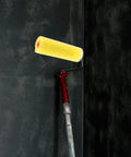 10 Piece Pack of Heavy Duty Sponge Paint Roller Sleeves on a roller handle painting a dark wall surface.