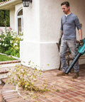 Man using Powerful 18V Cordless Blower Kit With 459 CFM 116 MPH Brushless Motor Cruise Control on patio to blow leaves