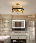 Modern bathroom interior with gold circular ceiling light fixture over a marble bathtub and vanity area.