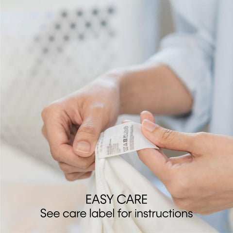 Person holding care label of Duck Solid Box Cushion Sofa Slipcover One Piece With Elastic Seat Seam Relaxed Fit No Fuss 100 Percent Cotton Duck Canvas.