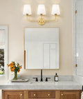 Top Tier Three Light Brushed Gold Vanity Lights With Flared White Fabric Shades Smooth Bathroom Mirror Fixture mounted above a wide mirror.
