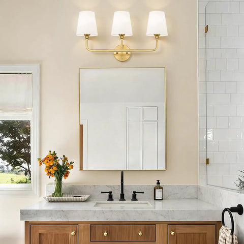 Top Tier Three Light Brushed Gold Vanity Lights With Flared White Fabric Shades Smooth Bathroom Mirror Fixture mounted above a wide mirror.