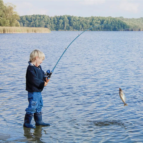 Child fishing in lake using portable kids fishing rod set 2 pack telescopic poles with rod and reel combos in blue.