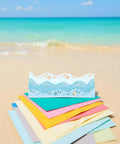 Beach Wave Metal Cutting Dies Set For Scrapbooking And Card Making placed on colorful paper sheets by ocean shore.