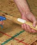 Applying Heavy Duty Waterproof Polyurethane Glue In Rich Brown to a wooden piece with a spray bottle on a workshop table.