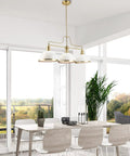 Three Light Linear Chandelier In Matte White With Brass Accents hanging over modern dining table in bright room.