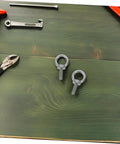 Stainless Steel Eye Bolt Anchor With Closed Ring M6x20 Deep Anchorage For Concrete And Machinery Mounting Includes Spring Washer Flat Washer And Nylon Locking For Solid Strength And Easy Hookups, two M6 eye bolts on green wood