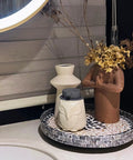 12 Inch Wooden Lazy Susan With Mother Of Pearl Inlay Smooth Spinning Turntable Serving Tray holding vases and dried flowers on a counter.